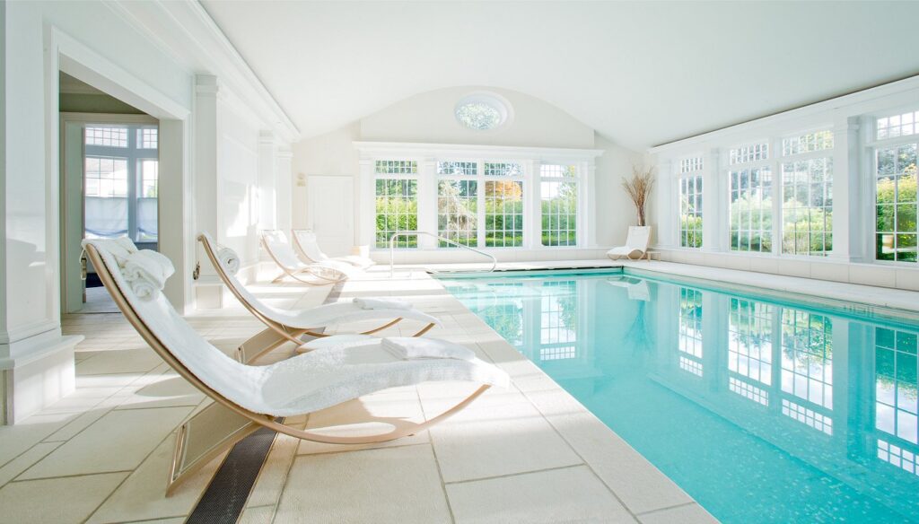 Indoor swimming pool at Mayflower Inn surrounded by arched windows and tranquil garden views